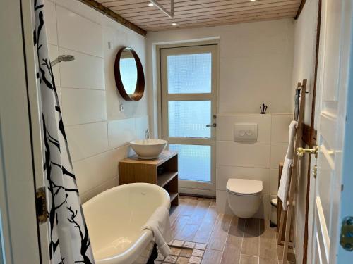 a bathroom with a tub and a toilet and a sink at Noorbohandelens Bed & Breakfast in Stege