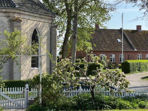 a white fence in front of a church at Noorbohandelens Bed & Breakfast in Stege