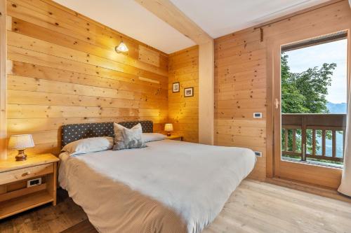 a bedroom with wooden walls and a bed with a window at Agritur El Casel in Brentonico