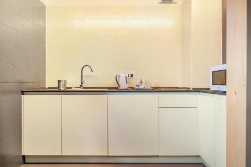 a kitchen with white cabinets and a sink at Agritur El Casel in Brentonico