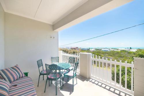 a balcony with a table and chairs and a view of the ocean at Land's Edge Eco Friendly Cottages and Apartments in Struisbaai