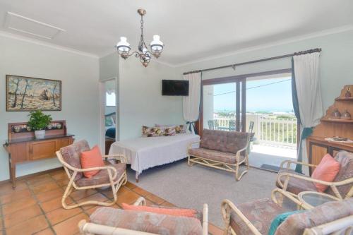 a living room with a bed and chairs and a window at Land's Edge Eco Friendly Cottages and Apartments in Struisbaai
