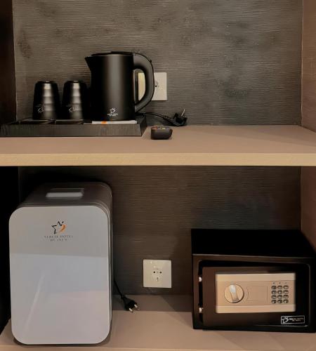 a microwave under a counter with a coffee pot on top at Nebula Hotel by Ine's in Assendelft