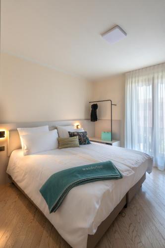 a large white bed with a green blanket on it at WANDERLUST HOTEL - SUITE & SPA - APARTMENTS & VILLAS - Bardolino, Lago di Garda - Verona in Bardolino