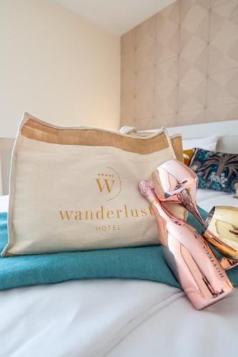 a hotel bag and pair of shoes sitting on a bed at WANDERLUST HOTEL - SUITE & SPA - APARTMENTS & VILLAS - Bardolino, Lago di Garda - Verona in Bardolino