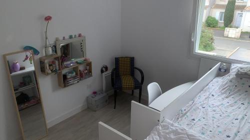 une chambre avec un lit, une chaise et une fenêtre dans l'établissement maison 3 chambres à 5 min du port de La Rochelle, à La Rochelle