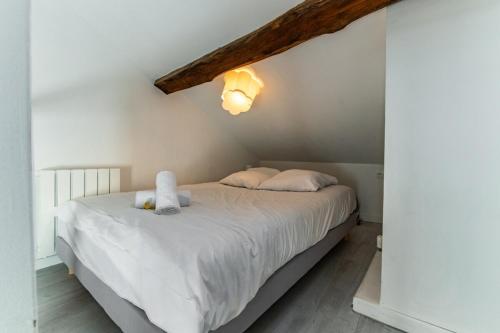 une chambre avec un lit avec des draps blancs et des oreillers dans l'établissement Le Nid - Duplex, à Dijon