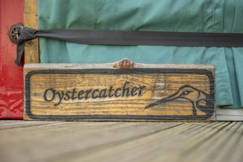 阿斯克里格Oystercatcher的一块木牌子，上面写着“orchestlater 坐在床上”