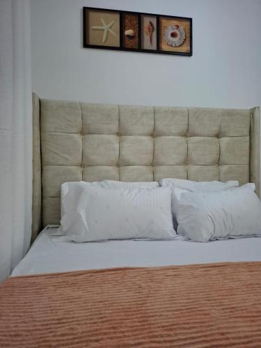 a bed with a large headboard and two pillows at The Cozy house in Nairobi