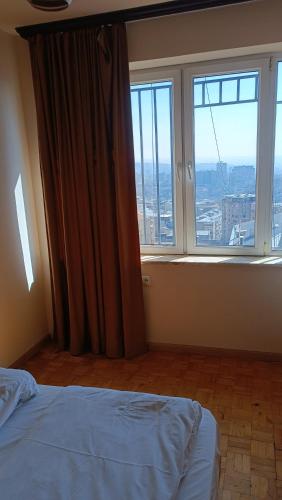 a bedroom with a bed and a large window at Orbeli Apartment in Aghk'ilisa