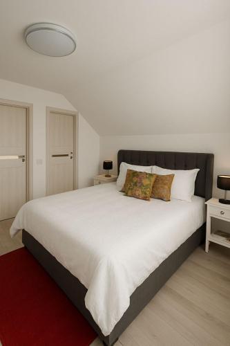 a bedroom with a large white bed with a red rug at Casa Luminița in Vama Buzăului