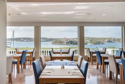 a restaurant with tables and chairs and a view of the water at Seth Agamenon in Es Castell