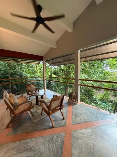 a living room with chairs and a ceiling fan at Ambong Rainforest Retreat in Pantai Cenang
