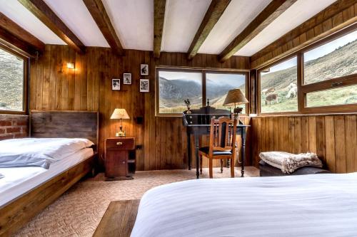 1 Schlafzimmer mit 2 Betten, einem Schreibtisch und Fenstern in der Unterkunft Chimborazo Lodge in Chimborazo