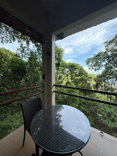 a glass table and chair on a balcony with two windows at Ambong Rainforest Retreat in Pantai Cenang