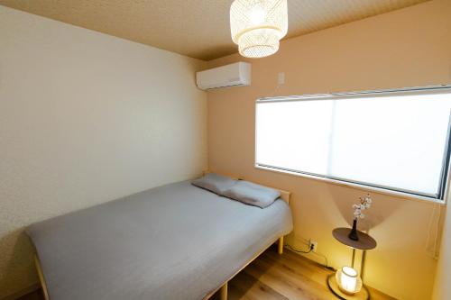 a small bedroom with a bed and a window at Shinimamiya Ebisu 戎 in Osaka