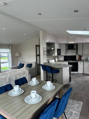 une cuisine et un salon avec une table en bois et des chaises bleues dans l'établissement Oakmont 4 - Lodge with Hot Tub, à Allerthorpe