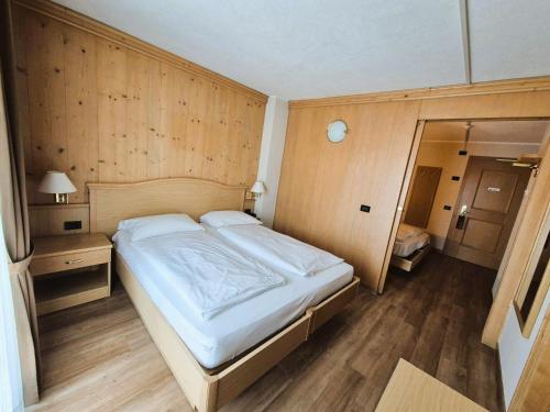 a large bed in a room with wooden walls at Hotel Angelica in Livigno