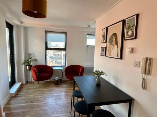 a living room with a table and chairs and windows at City Centre 2 bed apartment with a balcony in Manchester