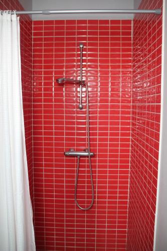 - une douche carrelée de rouge avec un mur rouge dans l'établissement Petit studio à la ferme à Mastaing, à Mastaing