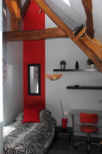 Cette chambre comprend un lit et un mur rouge. dans l'établissement Petit studio à la ferme à Mastaing, à Mastaing