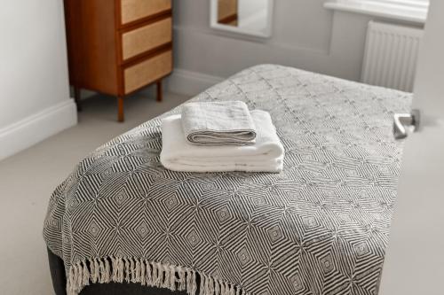a bed with a pile of towels on top of it at Brand NEW 2 BR Fulham Apartment Near Tube Station COZY in London