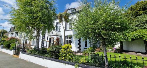 a white house with trees in front of it at Holcombe House Guest House in Llandudno