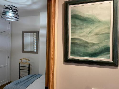 a painting hanging on a wall next to a bed at Casa del concejo segovia in Segovia