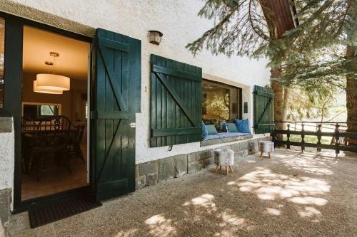 a house with green shutters and a couch on a porch at CASA FIR by Cardi Suites in Formigal