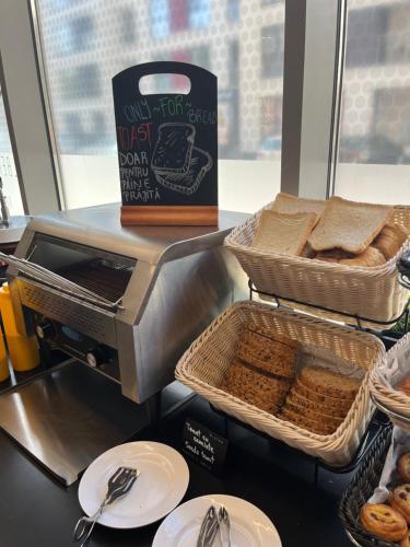 a counter with baskets of bread and a box of bread at ibis Bucharest Politehnica in Bucharest