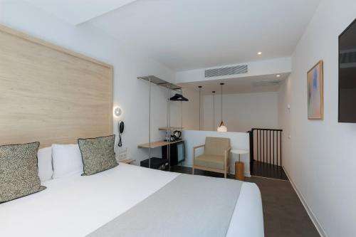a bedroom with a white bed and a chair at Casa Lit Barcelona in Barcelona