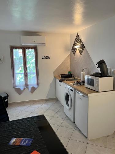 une cuisine avec un lave-linge et un micro-ondes dans l'établissement Épices 1 au cœur du centre ville historique de Serignan, à Sérignan