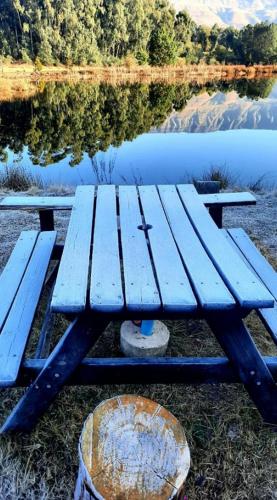 a blue picnic table sitting next to a lake at Island Cabin in Mpofane