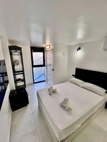 a white bedroom with a large white bed with a ladder at MT Boutique Suites y Apartamentos - Adults Only - in Mataró