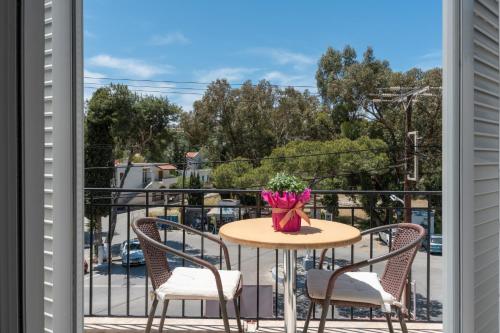 a table with chairs and a vase of flowers on a balcony at Ilias Voula Studios in Panormos Kalymnos