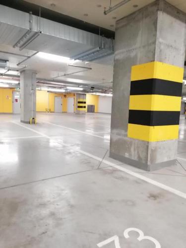 an empty parking garage with a yellow and black pillar at Luksusowy apartament z widokiem, basenem i sauną Hanza Tower Szczecin in Szczecin
