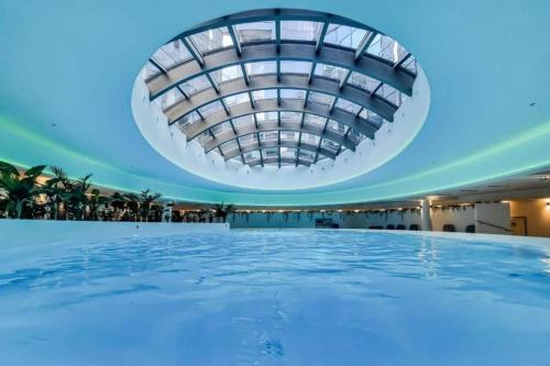 a swimming pool in a building with a domed ceiling at Luksusowy apartament z widokiem, basenem i sauną Hanza Tower Szczecin in Szczecin