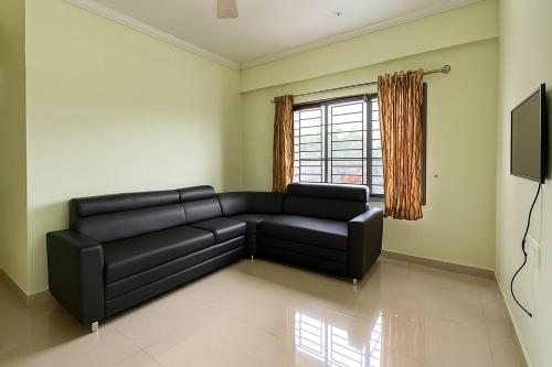 a living room with a black couch and a window at Stay Near Carithas & Matha Blue Bells by Haritha homes in Kottayam