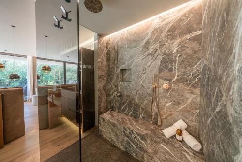 a bathroom with a shower with a stone wall at Boutique Hotel AMARIL in Castelbello-ciardes