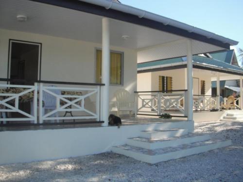 a white house with a cat sitting on the porch at Pension Turiroa " Chez Olga" in Avatoru
