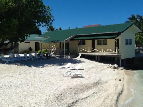 a house on a beach with chairs and a building at Pension Turiroa " Chez Olga" in Avatoru