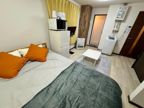 a bedroom with a bed with orange pillows on it at 札幌中島公園徒歩圏内の宿泊施設室内はとてもおしゃれで綺麗な室内空間 in Sapporo