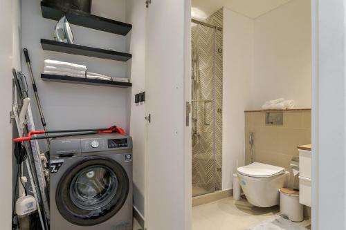 a bathroom with a washing machine and a toilet at Cozy One Bedroom Near Dubai Hills Mall in Dubai