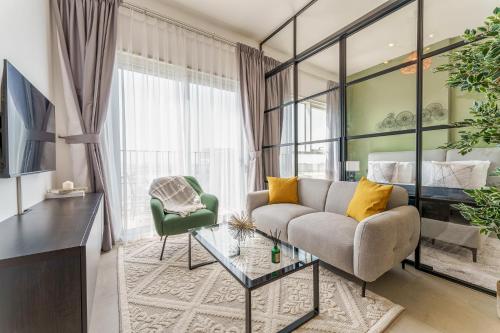a living room with a couch and a glass table at Cozy One Bedroom Near Dubai Hills Mall in Dubai