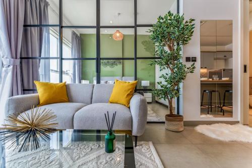 a living room with a gray couch and yellow pillows at Cozy One Bedroom Near Dubai Hills Mall in Dubai
