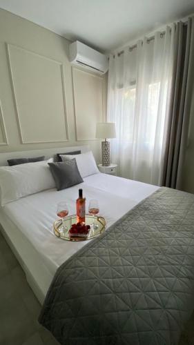 a bed with a tray with a bottle and two glasses at Morfeas Residence in Chrysoupolis