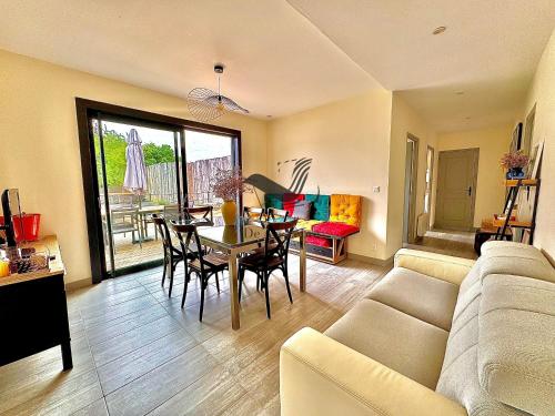 un salon avec un canapé, une table et des chaises dans l'établissement La Verrerie - Maison coeur de ville avec jardin, à La Tremblade