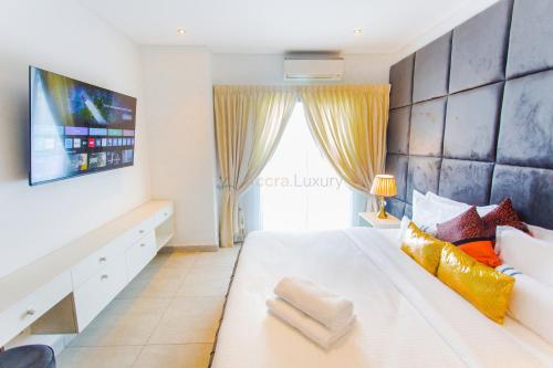 a bedroom with a large white bed and a tv at Accra Luxury Apartments @ The Signature in Accra