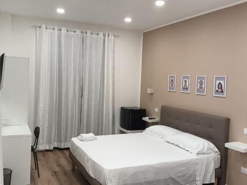 a bedroom with a white bed and a window at Al Carmine Rooms in Milazzo