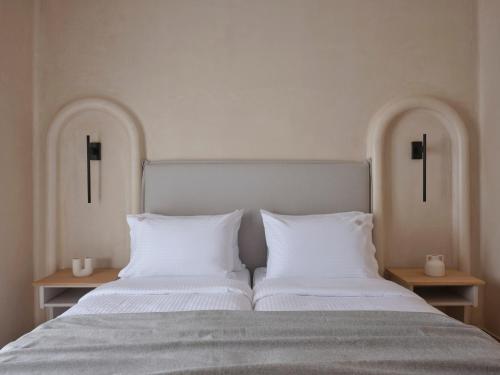 a bed with two white pillows and two tables at Salt Suites Paros in Naousa